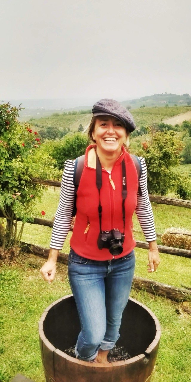 Alessandra pisando uvas em uma tina entre os vinhedos