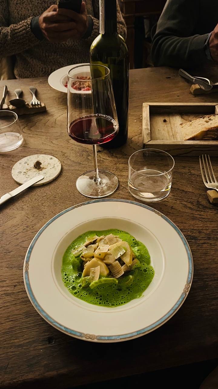 Um prato da cozinha local e uma taça de vinho tinto sobre uma mesa de madeira