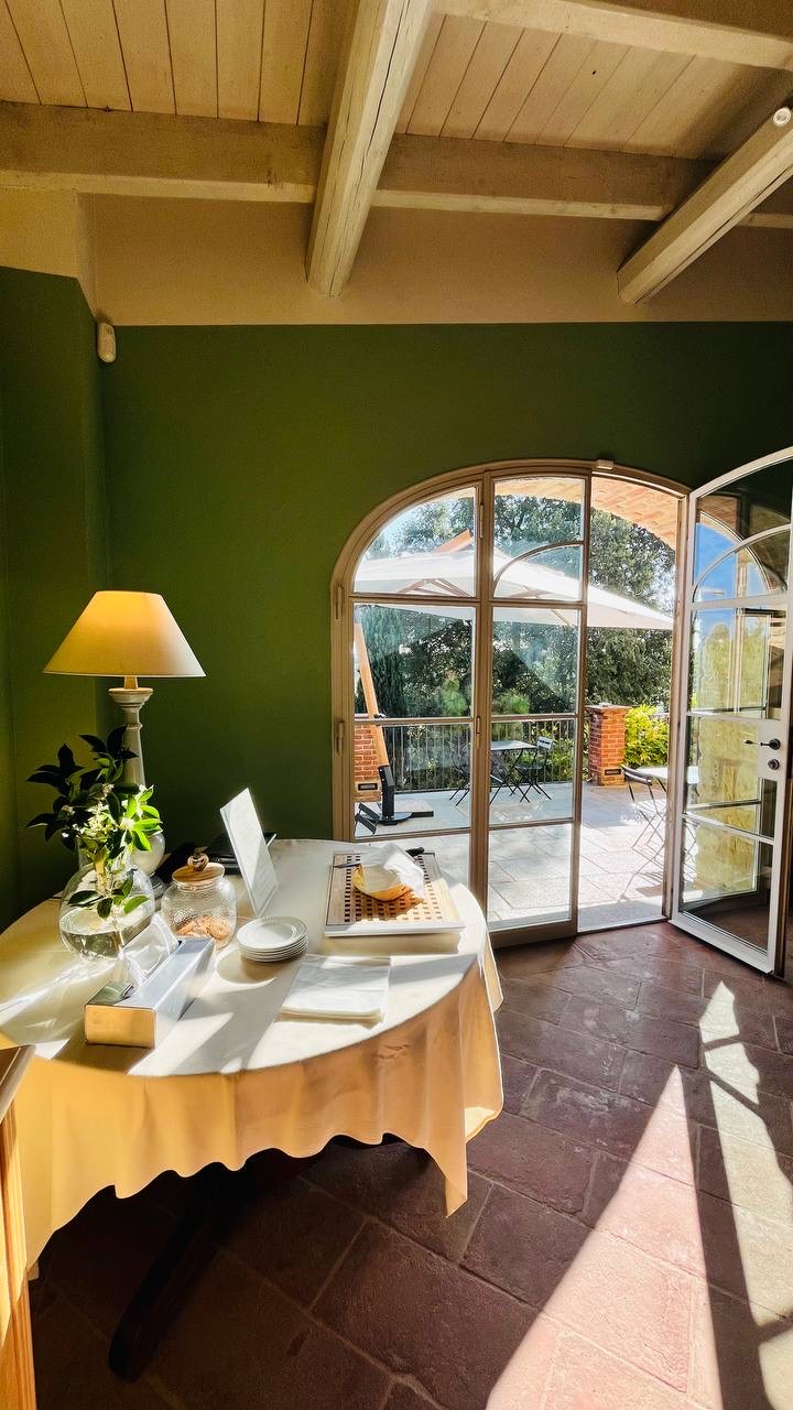 Sala de paredes verdes com porta em arco aberta para um terraço ensolarado